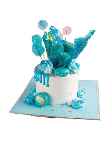 Elegant blue cake with macarons, candy shards, and drip design.