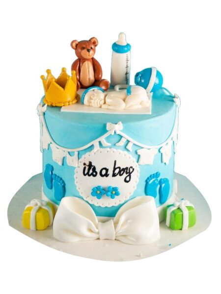 Blue baby shower cake with teddy bear, crown, baby figurine, and “It’s a Boy” topper.